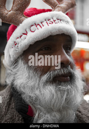 Big Issue seller in Liverpool City Centre, Merseyside, wearing Christmas festive hat, Europe EU