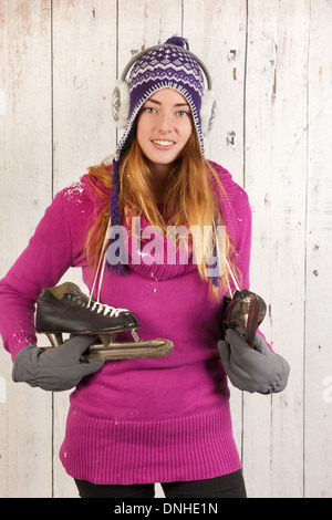 Portrait of woman in winter with hat, ear warmers and ice skates Stock Photo