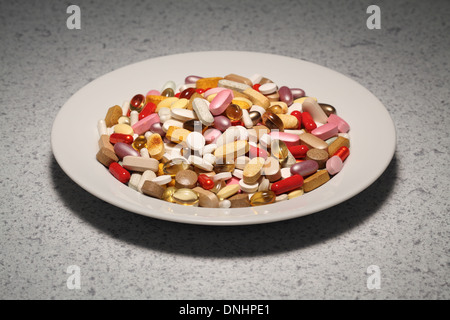 A round plate filled with mixed vitamin supplements- pills, tablets and capsules. Stock Photo