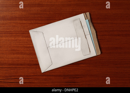 An air mail postage envelope slightly worn and torn on a wood surface. Stock Photo