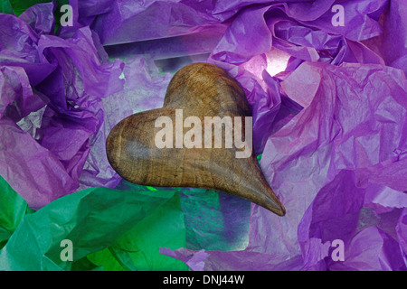 Antique wooden heart denoting love, in a gift box with colored tissue paper. Stock Photo
