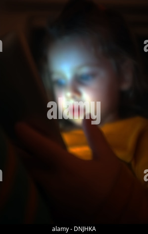 Little girl plays with her tablet Stock Photo