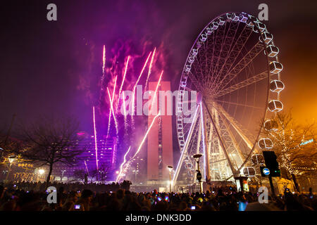 Happy New Year celebrations as crowds enjoy amusement rides with lights in Manchester, UK January, 2014. This year for the first time Piccadilly Gardens hosted Manchester's privately sponsored New Year's Eve celebrations and fireworks display. The event featured a 10-minute firework display, ferris wheel, park, fun, sky, amusement, entertainment, travel, city, carnival, fair, ride, blue, carousel, attraction, leisure, festival, night circle. New Years Eve Big Wheel rides on the 60m-high, 42 pod spinning ride until 1am. Stock Photo