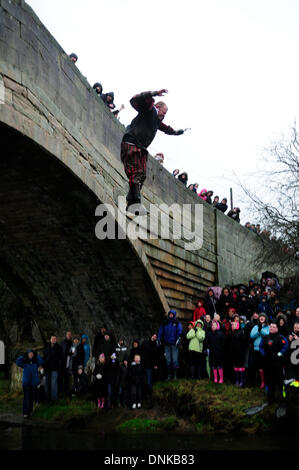 Mapleton, Derbyshire, UK. 01st January2013. New years day bridge jump for charity .Teams in fancy dress took part in the annual event in the village of Mapleton,starting with a boat race  down the river dove then a short run to the bridge where they then jumped in to the river Dove,swam to the edge and raced up to the pub for the finsih ,were a warm drink and clothes were in order.The conditions very windy and heavy rain kept the crowds down this year. Credit:  Ian Francis/Alamy Live News Stock Photo