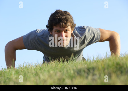 Close up of a man doing pushups on the grass with the horizon in the background Stock Photo