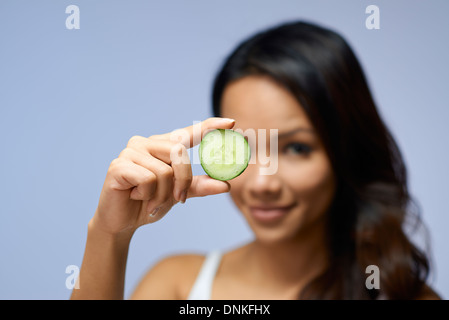 Young people and body care with portrait of happy asian girl smiling with cucumber for skin treatment Stock Photo