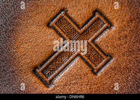 Leather Cross depicted on a leather background for wallpaper or copy space. Stock Photo