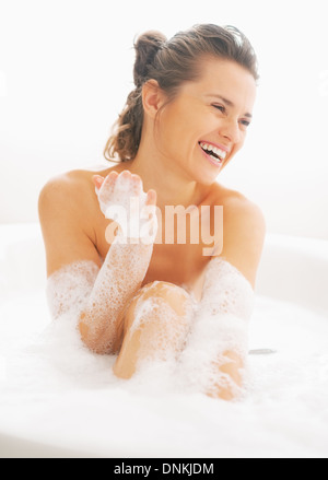 Smiling young woman playing with foam in bathtub Stock Photo