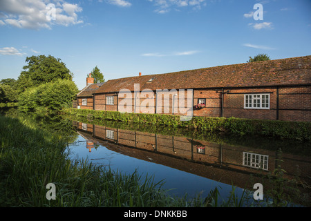 Timbered brick building on River Wey at Pyrford, Surrey, UK in summer with reflection in still water Stock Photo