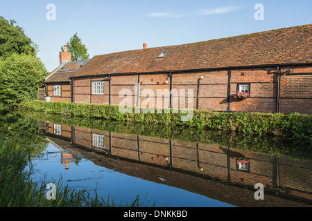 Timbered brick building on River Wey at Pyrford, Surrey, UK in summer with reflection in still water Stock Photo