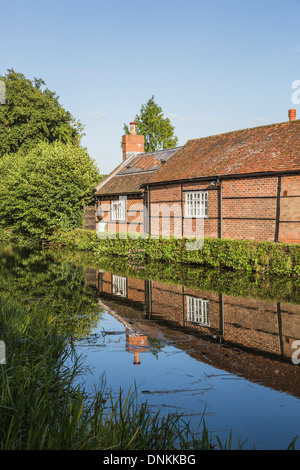 Timbered brick building on River Wey at Pyrford, Surrey, UK in summer with reflection in still water Stock Photo