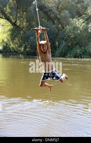 Briescht, Germany, boy swinging on a rope over the water of the Spree Stock Photo