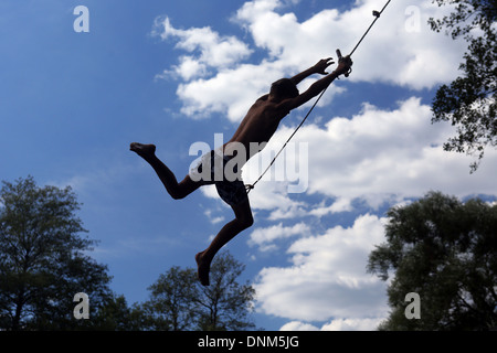 Briescht, Germany, silhouette, boy swinging on a rope through the air Stock Photo