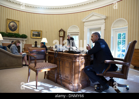 US President Barack Obama uses his speaker phone during a Congressional phone call in the Oval Office of the White House October 25, 2013 in Washington, DC. Stock Photo