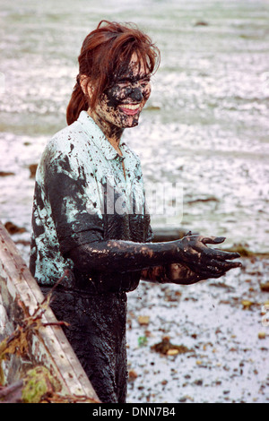 smiling woman covered in filth during traditional game of mud football on langstone locks mud flats portsmouth england uk Stock Photo