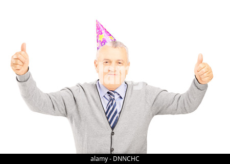 Happy mature gentleman with party hat giving thumbs up Stock Photo