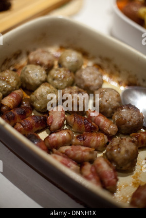 Close-up of roasted stuffing balls and pigs in blankets (small sausages wrapped in bacon) on Christmas Day Stock Photo