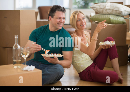 Couple eating sushi in new home Stock Photo