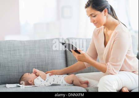 Mother playing with baby boy (2-5 months) and using digital tablet Stock Photo