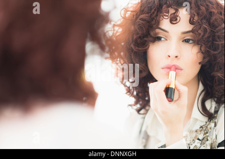 Beautiful brunette woman applying lipstick Stock Photo