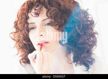 Studio shot of beautiful woman applying lipstick Stock Photo