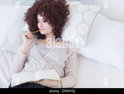 Beautiful woman lying in bed holding diary Stock Photo