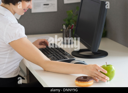 Businesswoman reaching for apple Stock Photo