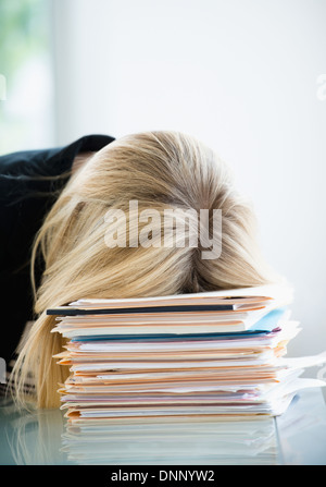 Businesswoman sleeping on stack of files Stock Photo