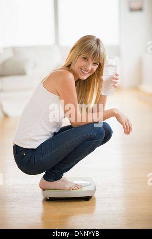 Portrait of woman crouching on weight scales Stock Photo