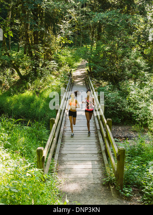 USA, Oregon, Portland, Two young women running over wooden footbridge Stock Photo