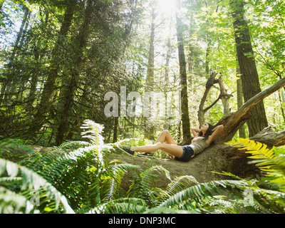 USA, Oregon, Portland, Young woman lying down on log Stock Photo