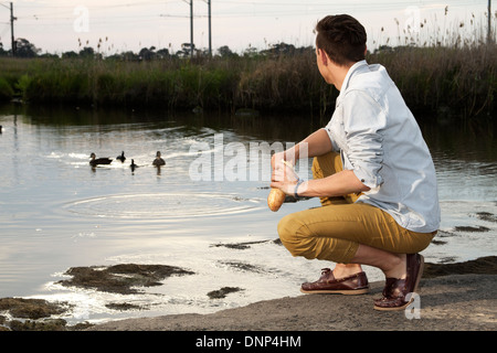 young man feeding ducks Stock Photo