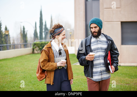 Hipster couple talking and drinking coffee to go at university campus Stock Photo