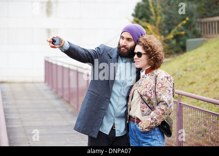 Couple taking a photograph of themselves with a smartphone outdoors Stock Photo