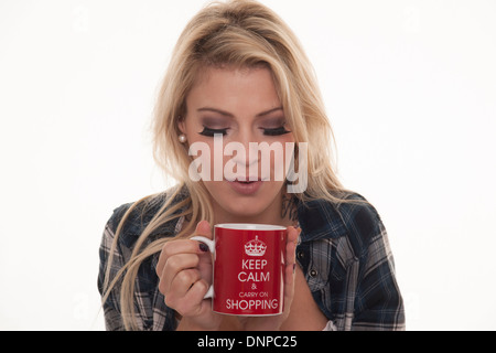 pretty blonde woman blowing on a hot mug of tea Stock Photo