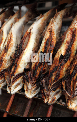 Steckerlfisch ('fish on sticks') cook over charcoal at the Oktoberfest in Munich, Germany. Stock Photo