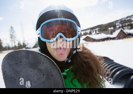 USA, Montana, Whitefish, Girl with snowboard sticking out her tongue Stock Photo