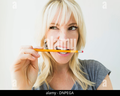 Woman holding pencil in her mouth Stock Photo