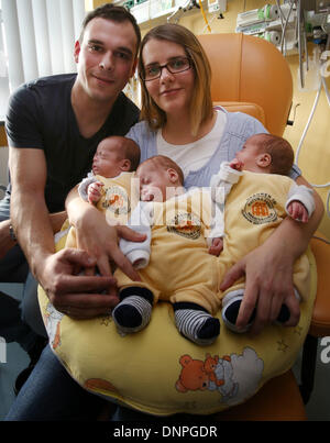 Rostock, Germany. 03rd Jan, 2014. The triplets (L-R) Till, Max and Ben lie in the arms of their parents Thomas and Marie Osswald in the South City Hospital in Rostock, Germany, 03 January 2014. Two and a half months after their birth on 22 October 2013, the triplets are now discharged home. The boys were born with a weight of 1200 to 1320 grams after only 29 weeks of gestation. Photo: Bernd Wuestneck/dpa/Alamy Live News Stock Photo