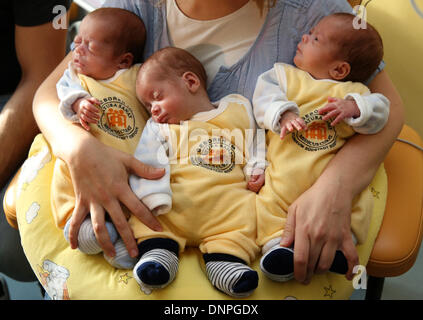 Rostock, Germany. 03rd Jan, 2014. The triplets (L-R) Till, Max and Ben lie in the arms of their mother Marie Osswald in the South City Hospital in Rostock, Germany, 03 January 2014. Two and a half months after their birth on 22 October 2013, the triplets are now discharged home. The boys were born with a weight of 1200 to 1320 grams after only 29 weeks of gestation. Photo: Bernd Wuestneck/dpa/Alamy Live News Stock Photo