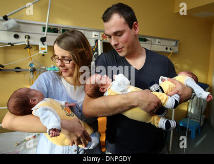 Rostock, Germany. 03rd Jan, 2014. The triplets (L-R) Till, Max and Ben lie in the arms of their parents Thomas and Marie Osswald in the South City Hospital in Rostock, Germany, 03 January 2014. Two and a half months after their birth on 22 October 2013, the triplets are now discharged home. The boys were born with a weight of 1200 to 1320 grams after only 29 weeks of gestation. Photo: Bernd Wuestneck/dpa/Alamy Live News Stock Photo