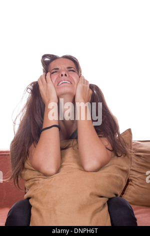 Disappointed cute girl crying with pillow on couch Stock Photo