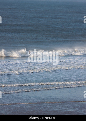 A lone surfer riding a wave off the North Devon coast at Putsborough. This stretch of coast is popular with surfers in the UK Stock Photo