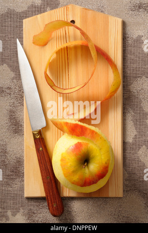 Overhead View of Apple with Skin Peeled on Cutting Board with Knife, Studio Shot Stock Photo