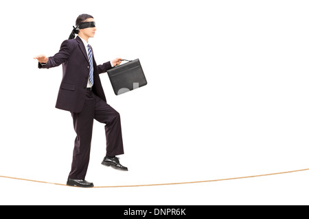 Blindfolded young businessman walking on rope Stock Photo