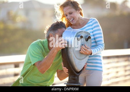 Mature Couple being Playful looking through Scenic Viewer on Pier, USA Stock Photo