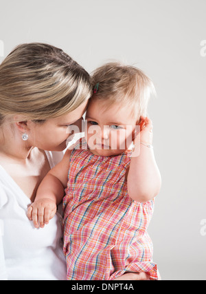Portrait of Mother holding Crying Baby Girl, Studio Shot Stock Photo