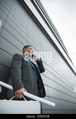 Businessman standing in front of wall of building using cell phone, Mannheim, Germany Stock Photo