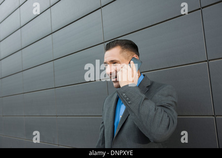 Close-up portrait of businessman standing in front of wall of building using cell phone, Mannheim, Germany Stock Photo