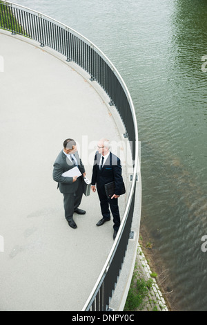 Mature businessmen standing on walkway talking, Mannheim, Germany Stock Photo